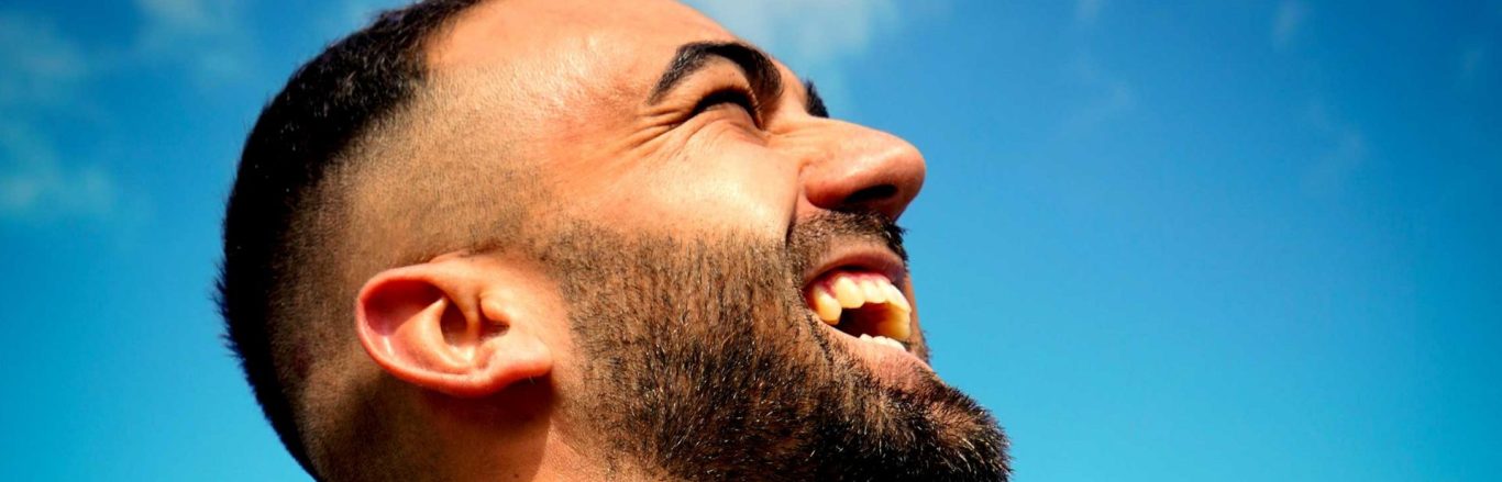 Freudig lachender Mann mit Vollbart